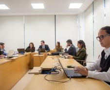 Em primeiro plano se vê uma mulher trans ao computador e ao fundo estão outras oito pessoas, todas ao computador. 