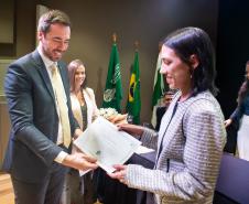 Imagem mostra nova servidora recebendo termo de posse das mãos do DPG. 