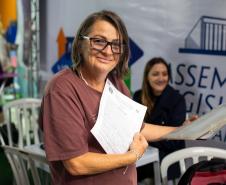 Mulher assistida pela DE-PR posa para a foto com os documentos ao fim do  atendimento ontem no ALEP nos Bairros.