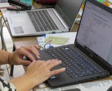 Imagem mostra detalhe de servidor teclando no computador em atendimento do mutirão em Tamarana. 