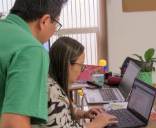 Imagem em que se vê servidor da DPE-PR conferindo dados de usuário em computador.  