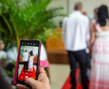 Em primeiro plano celular grava casal que está diante do juiz de paz. 