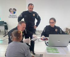 Servidores do Instituto de Identificação realizam a coleta de digitais para realização da identidade de uma mulher idosa que reside no Pequeno Cotolengo. 