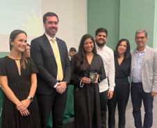 Nova defensora pública recebe sua carteira funcional ao lado de representantes da instituição e familiares. 