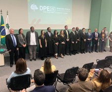 Novos defensores públicos empossados posam ao lado de representantes da instituição ao fim da cerimônia no auditório da instituição. 