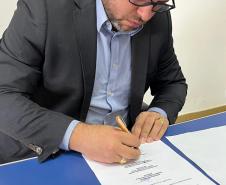 O Defensor Público João Victor Rozatti Longhi assina documento de aluguel social em Faxinal.
