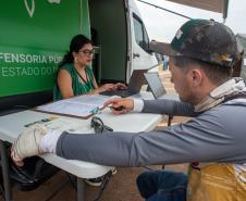 Assistente jurídica da Defensoria Pública realiza atendimento  na Van de Direitos de um homem com curativo na mão esquerda.  