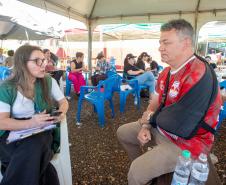 Servidora da DPE-PR realiza atendimento a um homem com tipoia no braço.