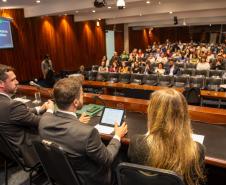 O DPG Matheus Munhoz e o coordenador do NUPED Luis Purgato aparecem de costas na mesa e ao fundo o público presente.