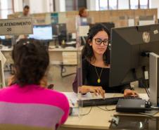 Imagem mostra uma mulher de costas recebendo atendimento na sede da Defensoria.