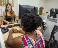 Imagem mostra mulher negra de costas sendo atendida em sede da DPE-PR em Paranavaí, no interior do estado. 