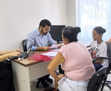 Imagem mostra um Defensor Público realizando atendimento a duas mulheres. 