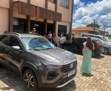 Mulher de vestido verde aparece de costas caminhando para a entrada da sede da Defensoria em Guarapuava. 