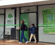 Mulher e criança vistos de longe chegam à sede da DPE-PR em Maringá para participar de Mutirão;