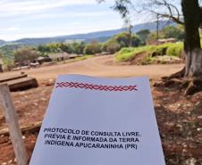 Imagem mostra o Protocolo de Consulta Livre, Prévia e Informada da Terra Indígena de Apucaraninha. Ao fundo se vê desfocada a comunidade.