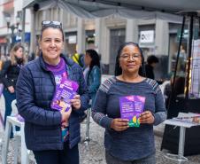 Mulheres seguram panfletos da Tenda Lilás.