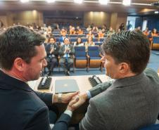 DPG Matheus Munhoz e presidente do TCE apertam as mãos, ao fundo a platéia.