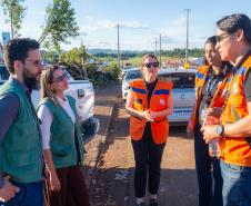 Imagem mostra a coordenadora do NUCRISE, defensora pública Ingrid Lima, conversando com as equipes da Defesa Civil do Estado.