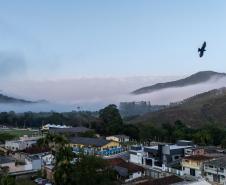 Imagem mostra vista aérea de Barra do Turvo, no Vale da Ribeira. No céu, um pássaro voa no canto esquerdo da imagem e a fundo montanhas cobertas por um mar de nuvens.