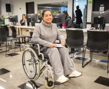 Mulher em cadeira de rodas posa para foto após atendimento da Defensoria Pública.  