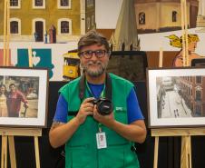 O fotógrafo Daniel Caron posa com os quadros da exposição.