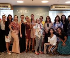 Vemos todos os participantes do evento em pé, juntos, esperando a foto ser tirada.