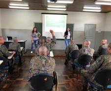 A imagem foi tirada novamente no fundo da sala. Vemos os soldados sentados nas carteiras e a equipe da DPPR na frente. Nessa imagem vemos que um dos alunos está com a mão levantada. 