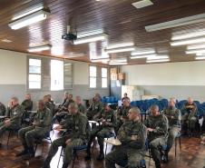 A imagem foi tirada na parte da frente focando nos alunos. Vemos esses prestando atenção na equipe da DPPR que está fora do quadro da imagem. 