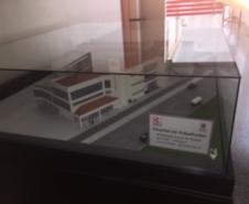 Na imagem vemos uma maquete do hospital do trabalho sendo exposta dentro de um envoltório de vidro. 