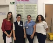 Na imagem vemos as Dra. Eliana Lopes e Patricia Mendes com outras duas pessoas na frente do banner informativo denominado "Cuidado Amigo da Mulher".