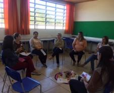 O grupo de responsáveis se encontra em formato de roda, todos sentados em cadeiras, conversando. 