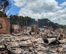 Foto mais ampla mostrando o que restou das estruturas pós incidente. Vemos muitos escombros e algumas paredes de tijolos ainda de pé.  