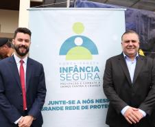 Na esquerda, o subdefensor público-geral, dr. Rodolpho Mussel de Macedo. Na direita, o secretário da Justiça, Família e Trabalho, Ney Leprevost. No meio, o cartaz da força-tarefa.  