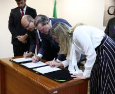 Mariana Lobo, defensora geral do Ceará no canto direito da imagem, Ministro Dias Toffoli, presidente do STF e do CNJ, no meio; e o defensor geral do Paraná, Eduardo Abraão, no canto esquerdo. Os três estão assinando o termo de cooperação. 