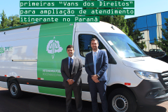 Na imagem tem o defensor público-geral e o coordenador da APE sorrindo para foto, em frente à van branca e verde da DPE-PR.