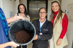 Três mulheres posam com a borra de café na sede da Defensoria. Toda borra do café passado na instituição será entregue no Ecoponto da Prefeitura de Curitiba onde vira adubo em um minhocário.   