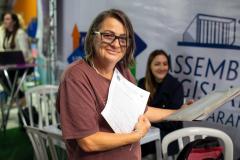 Mulher assistida pela DE-PR posa para a foto com os documentos ao fim do  atendimento ontem no ALEP nos Bairros.