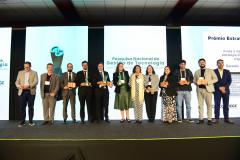 Imagem mostra os vencedores da Pesquisa Nacional de Transformação Digital e Gestão de Tecnologia nas Defensorias Públicas Estaduais posando no palco do Enastic, evento realizado em Foz do Iguaçu.