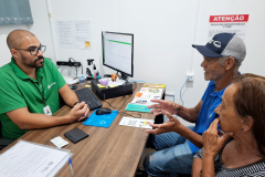 Servidor da DPE-PR atendendo casal de idosos durante mutirão do Concilia em Guaíra. 