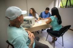 Imagem mostra um casal sendo atendido durante o Mutirão do NUDECON para pessoas com superendividamento. 
