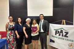 Na imagem vemos a Equipe Técnica da DPPR juntos, posando para a foto, do lado de um cartaz do evento.