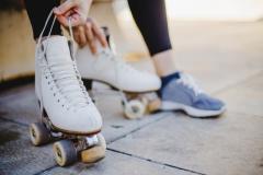 Imagem de uma menina sentada segurando laços de patins de rodas
