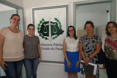 Da esquerda para a direita: Thaís Fondazzi Radecki, Tânia Cordeiro Aldivino, Mariana Gonzaga Amorin, Fabrícia Bronzel e Silvia Andreia Rocha. Legenda acessível: Na imagem estão as participantes olhando para a foto e sorrindo. Estão ao lado de um banner com a logo da defensoria, estão duas para a esquerda e três para a direita.