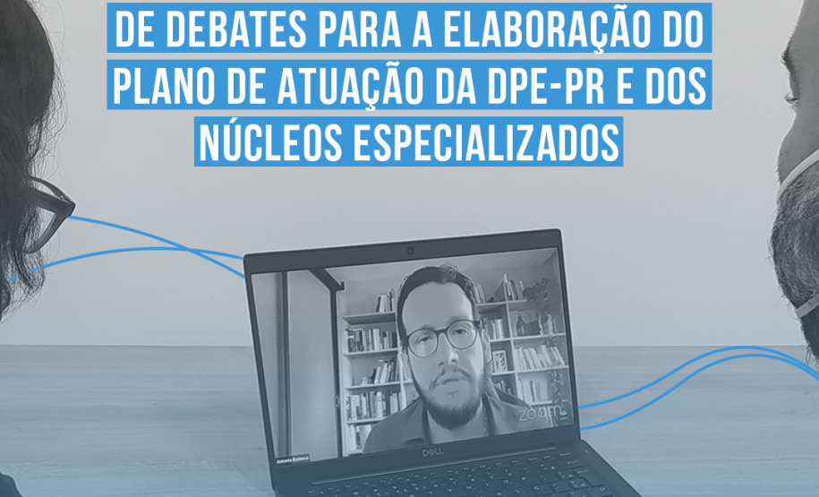 Duas pessoas assistem, em um notebook, um homem de barba e óculos em uma tela