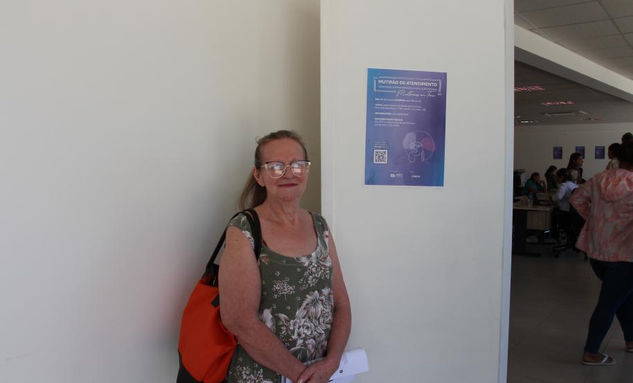 Imagem de usuária ao lado de cartaz de divulgação do mutirão