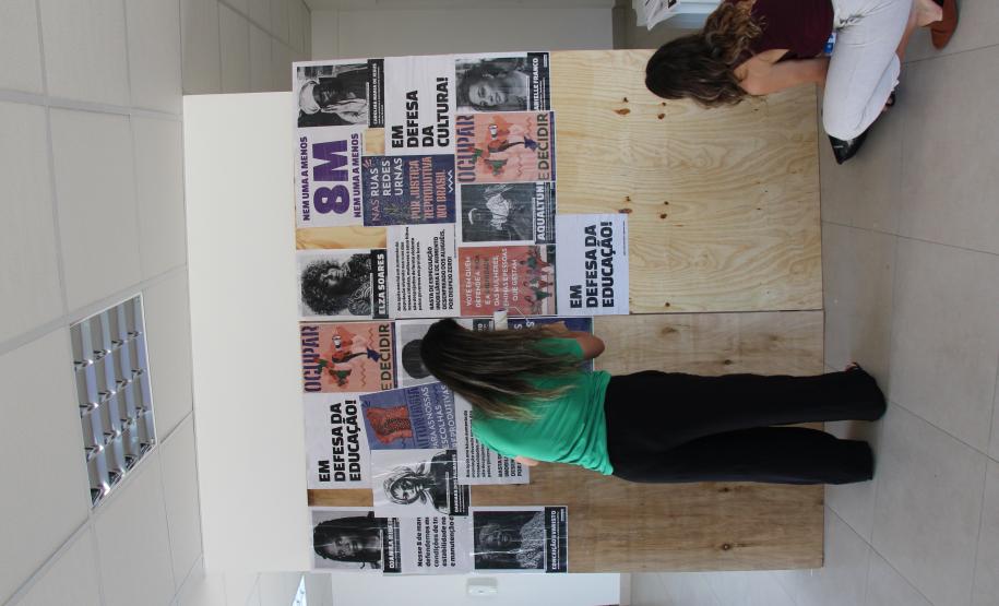 Imagem de mulheres colando os lambes durante intervenção artística