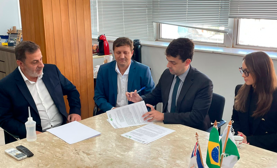 Imagem dos presentes sentados em uma mesa onde o defensor públic-geral assina alguns documentos