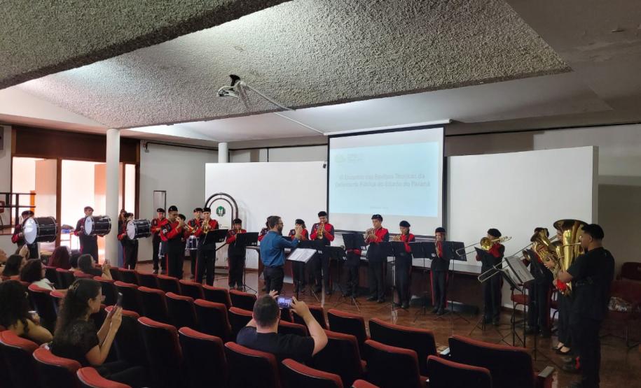 Imagem que mostra uma banda de metais formada por adolescentes se apresentando para a plateia do evento.