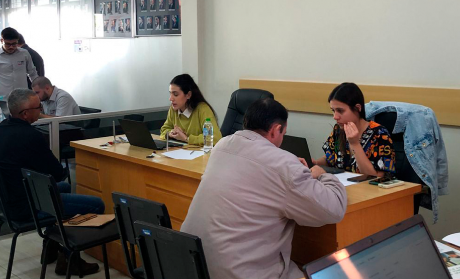 Imagem que mostra duas atendentes da Defensoria Pública, cada uma delas atende um homem.