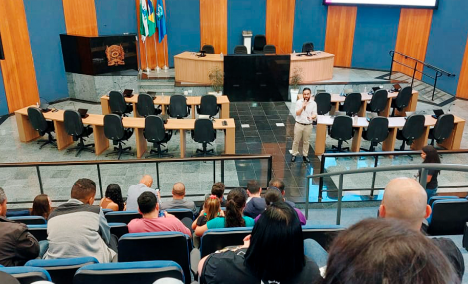 Imagem que mostra o defensor Fernando Redede falando para pessoas que aguardam atendimento para a entrega de DNA.